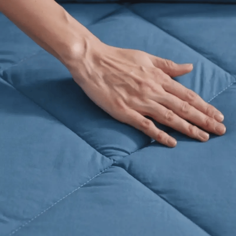 Une main posée sur la couette Peasy Sleep, matière douce et moelleuse